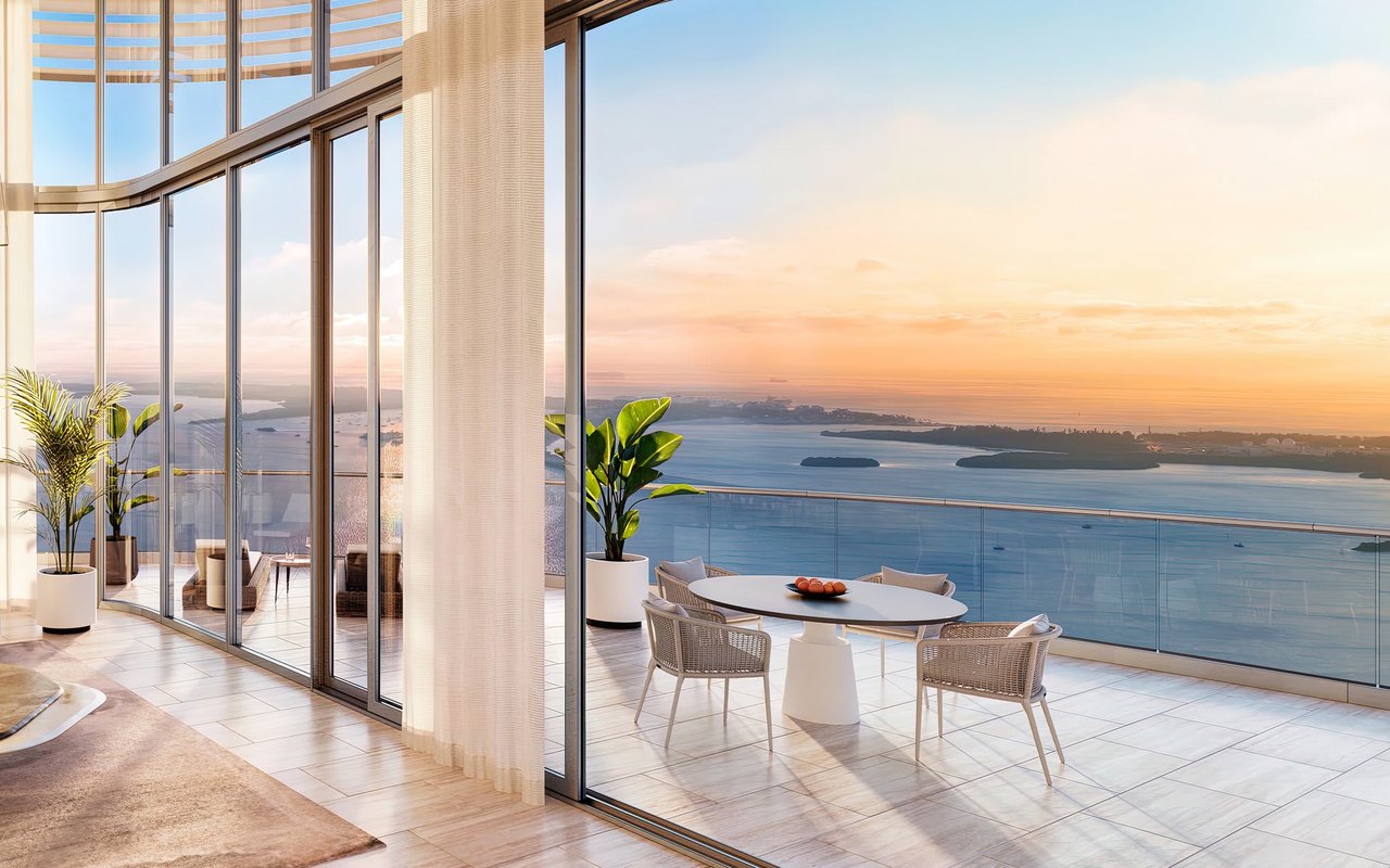 Furnished high-rise terrace with floor-to-ceiling windows and a bay view at sunset.