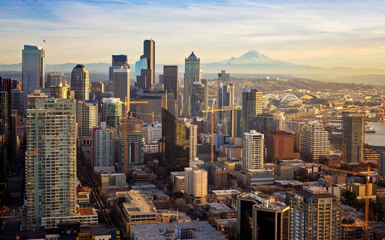 An expansive aerial view of the Seattle skyline on a bright day, featuring numerous tall buildings and skyscrapers.