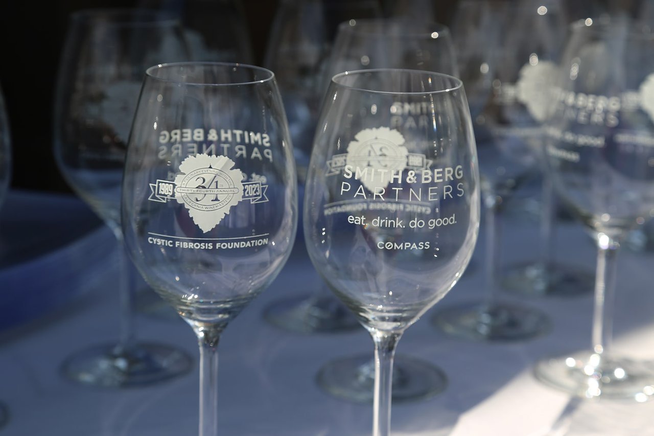  Two clear wine glasses are in the foreground, with several more blurred in the background.