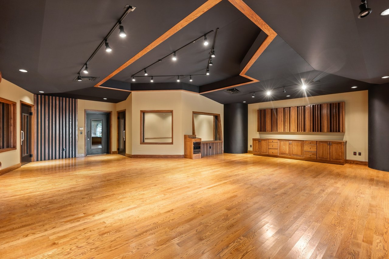 Vacant room with polished hardwood floors, a geometric black ceiling, and built-in wooden cabinetry.