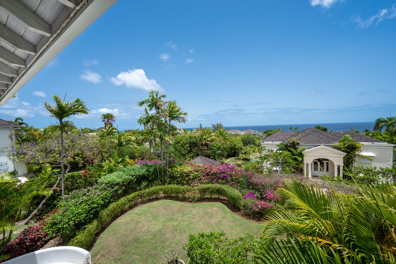 Tropical garden at Coconut Ridge 4 with palm trees, nearby villas, and a sea view.