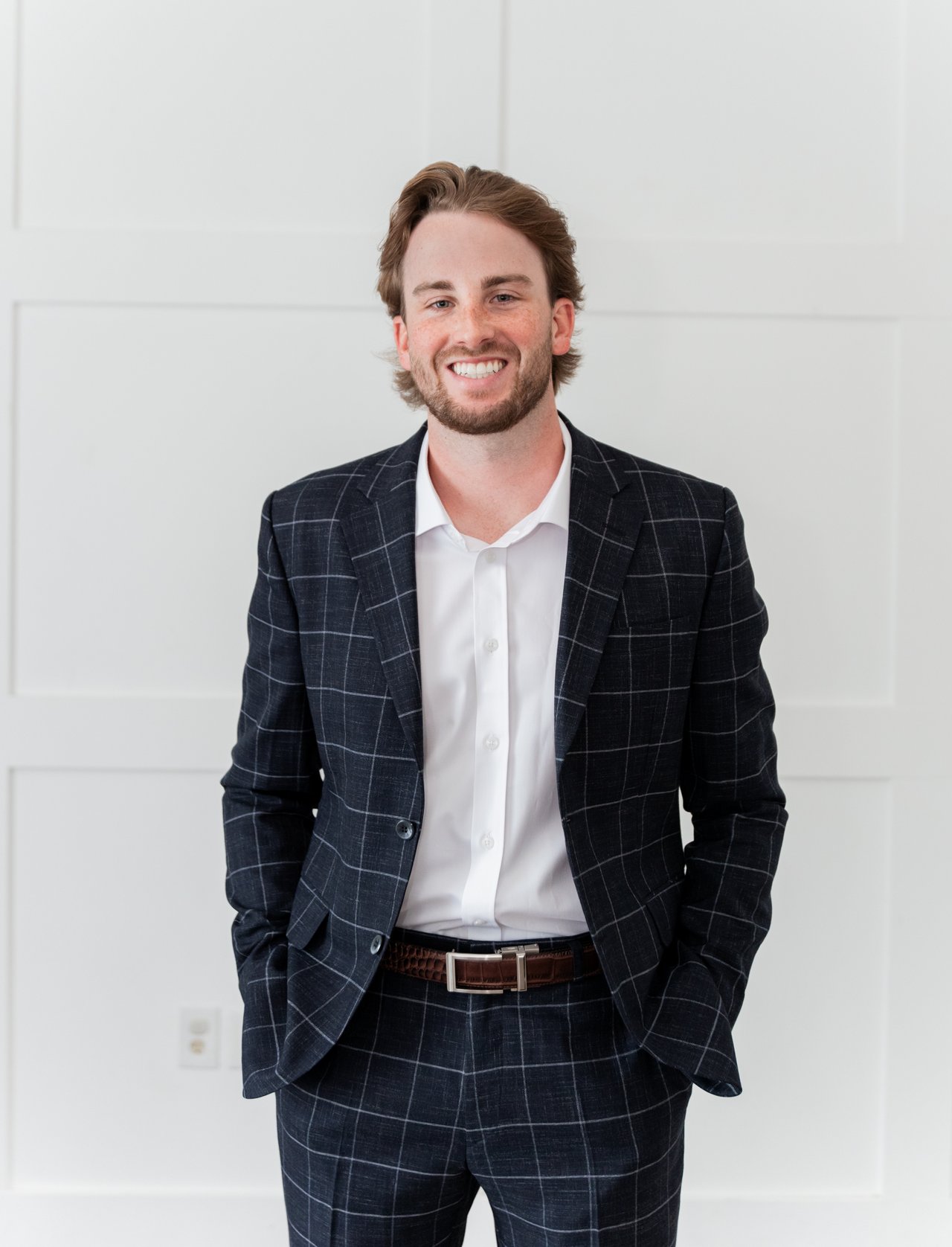 Bryson Bowen smiling in a navy windowpane suit and white shirt.