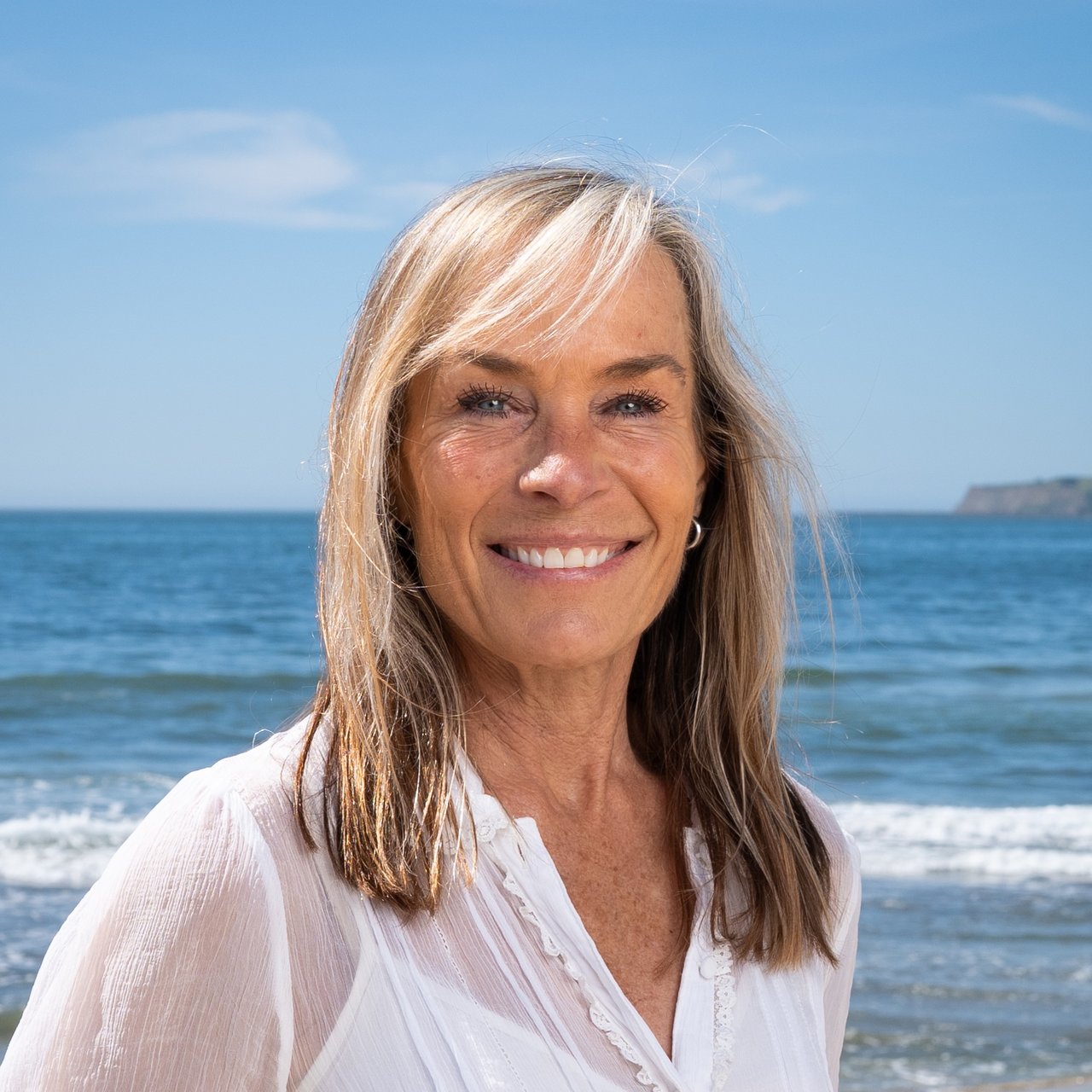 Corrine Bucher, Ocean Element Real Estate brand ambassador, standing on a Coastside beach in Half Moon Bay with ocean views in San Mateo County