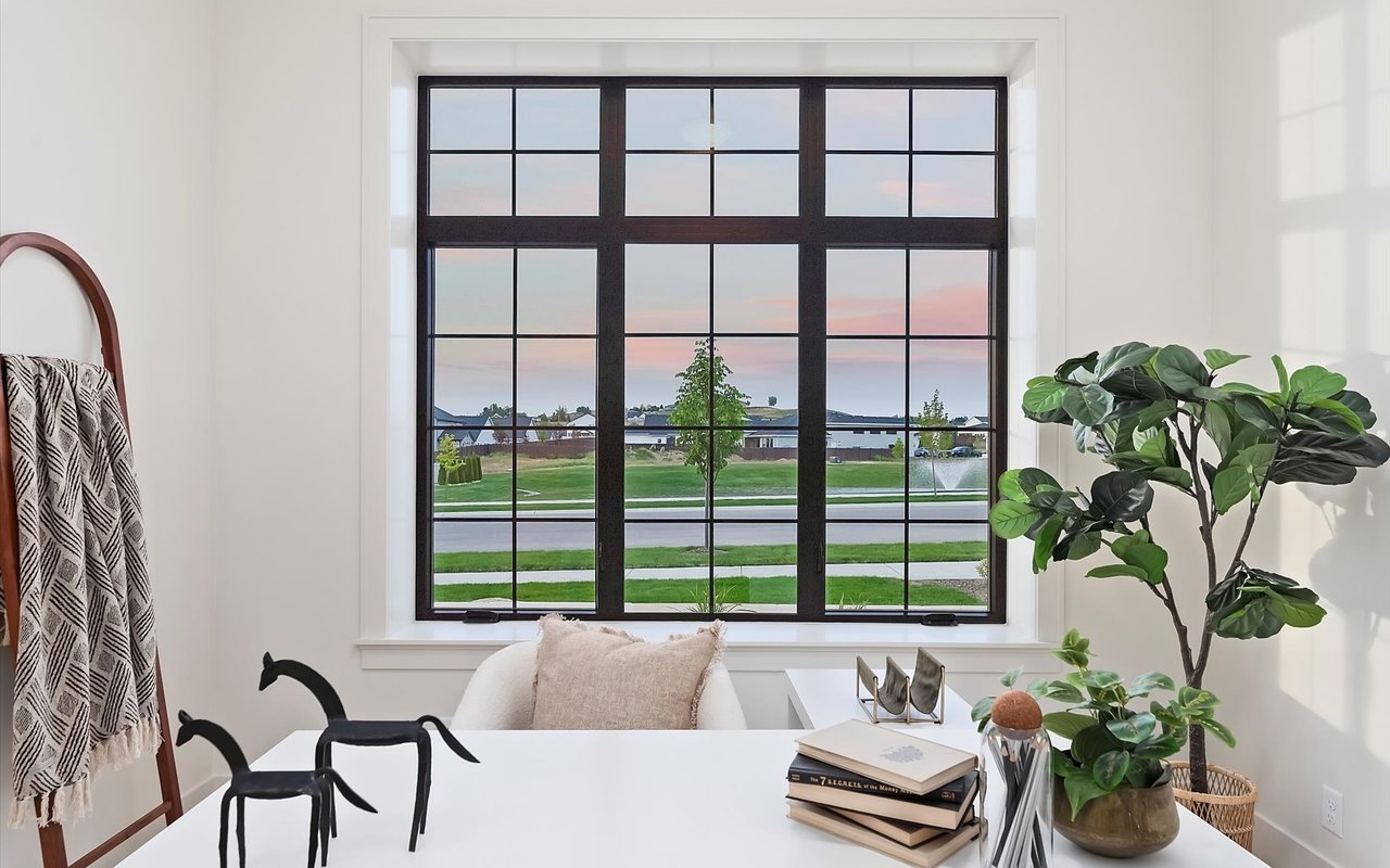 Home office in a new modern prairie home featuring black vinyl windows overlooking seasonal pond with fountain.
