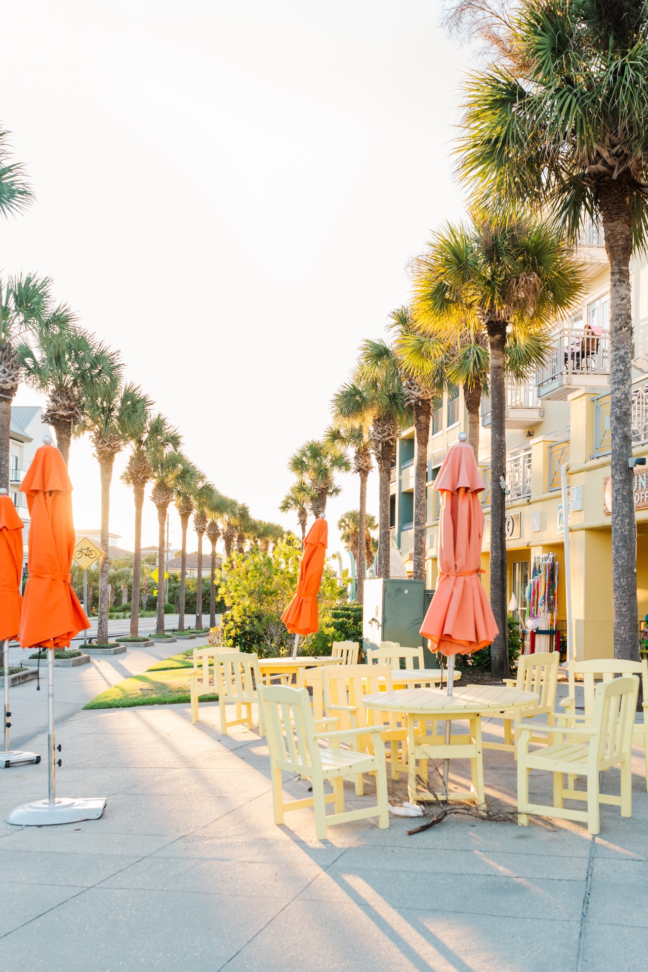 White Moorish stucco archway framing a palm-lined paver promenade at golden hour in Gulf Place on 30A, Florida