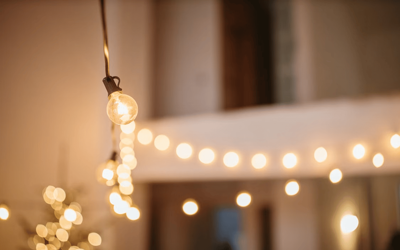 Glowing string lights hang indoors against a softly blurred room.