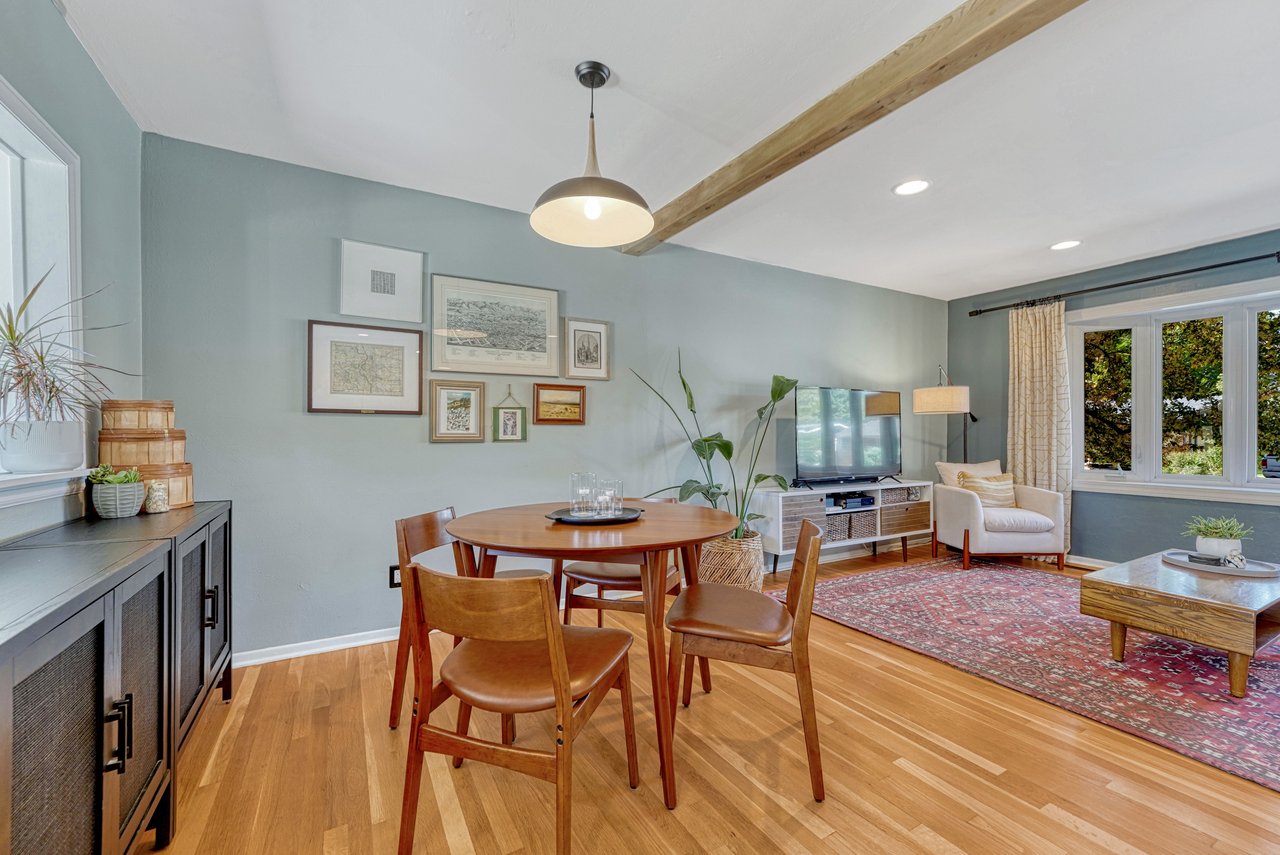 Dining area with a pendant light and hardwood floors between the living room and kitchen
