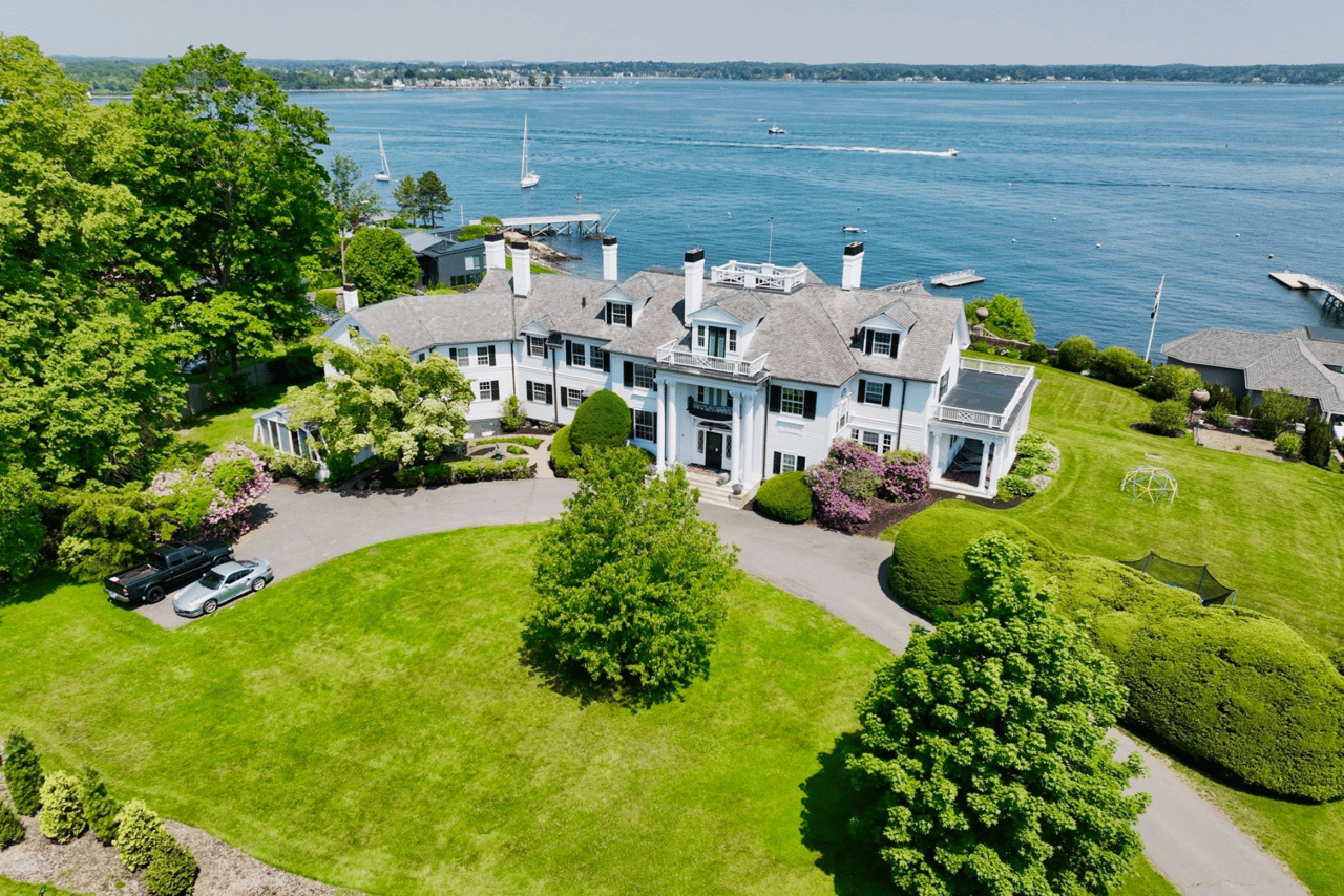 Aerial view of Broadmere Estate, a white waterfront home with broad lawns and a dock.