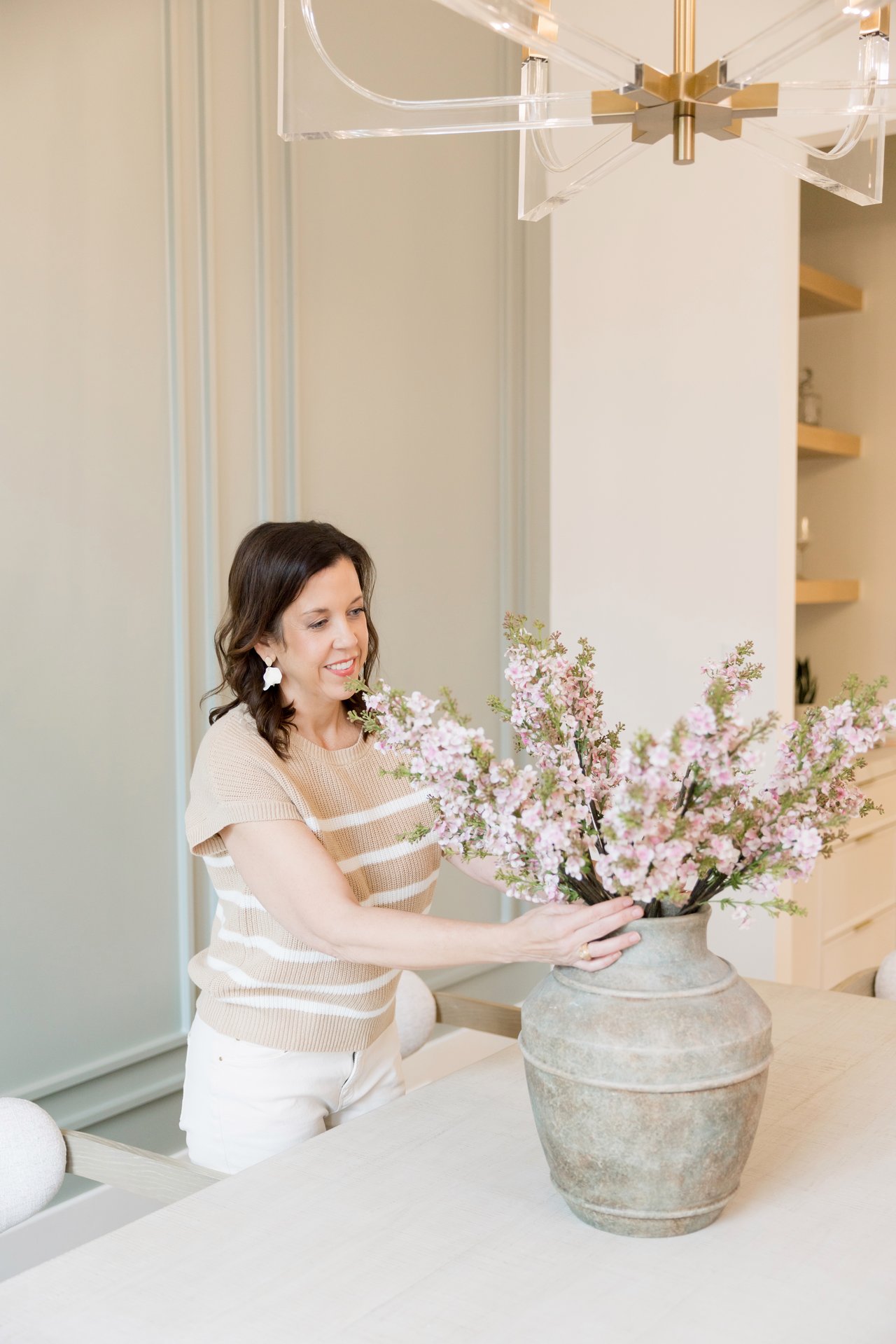 Woman arranging pink flowers in a large ceramic vase