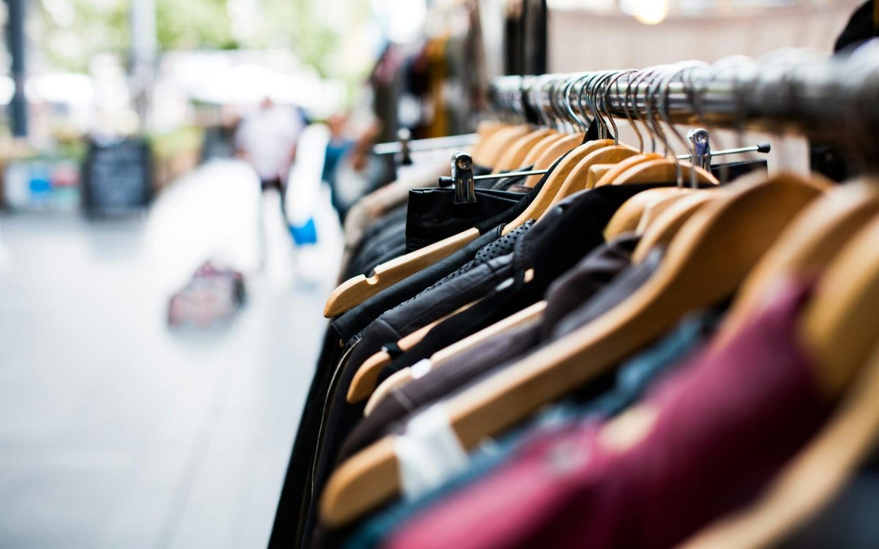  A shallow depth of field shot of a clothing rack filled with garments on wooden hangers, likely in a store or market.