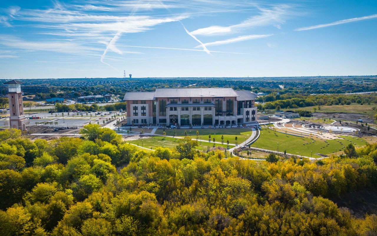 Aerial view of a landscaped campus building with a tower and tree-lined grounds.