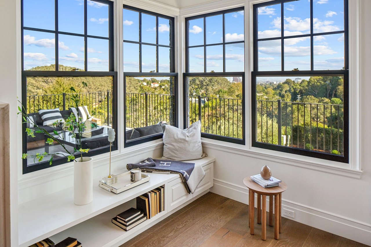  A bright and inviting bay window nook offers panoramic views of a lush green landscape and distant cityscape 