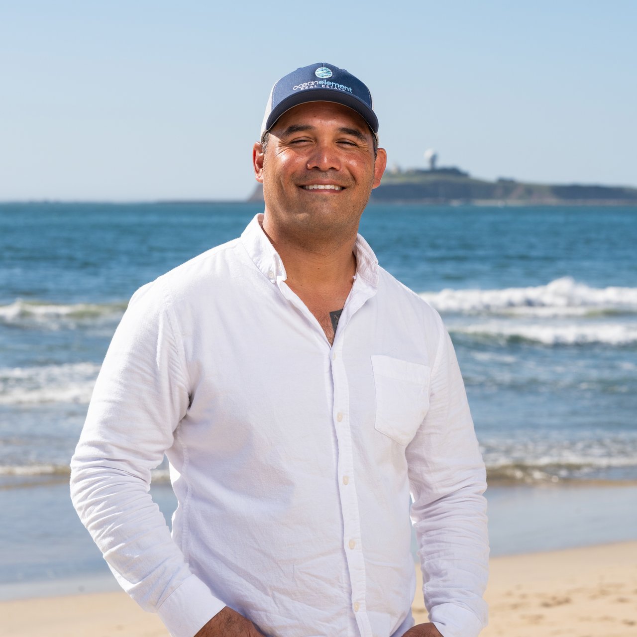 Gabe Weisbarth, real estate agent with Ocean Element Real Estate, standing on a beach in Half Moon Bay along the San Mateo County Coastside