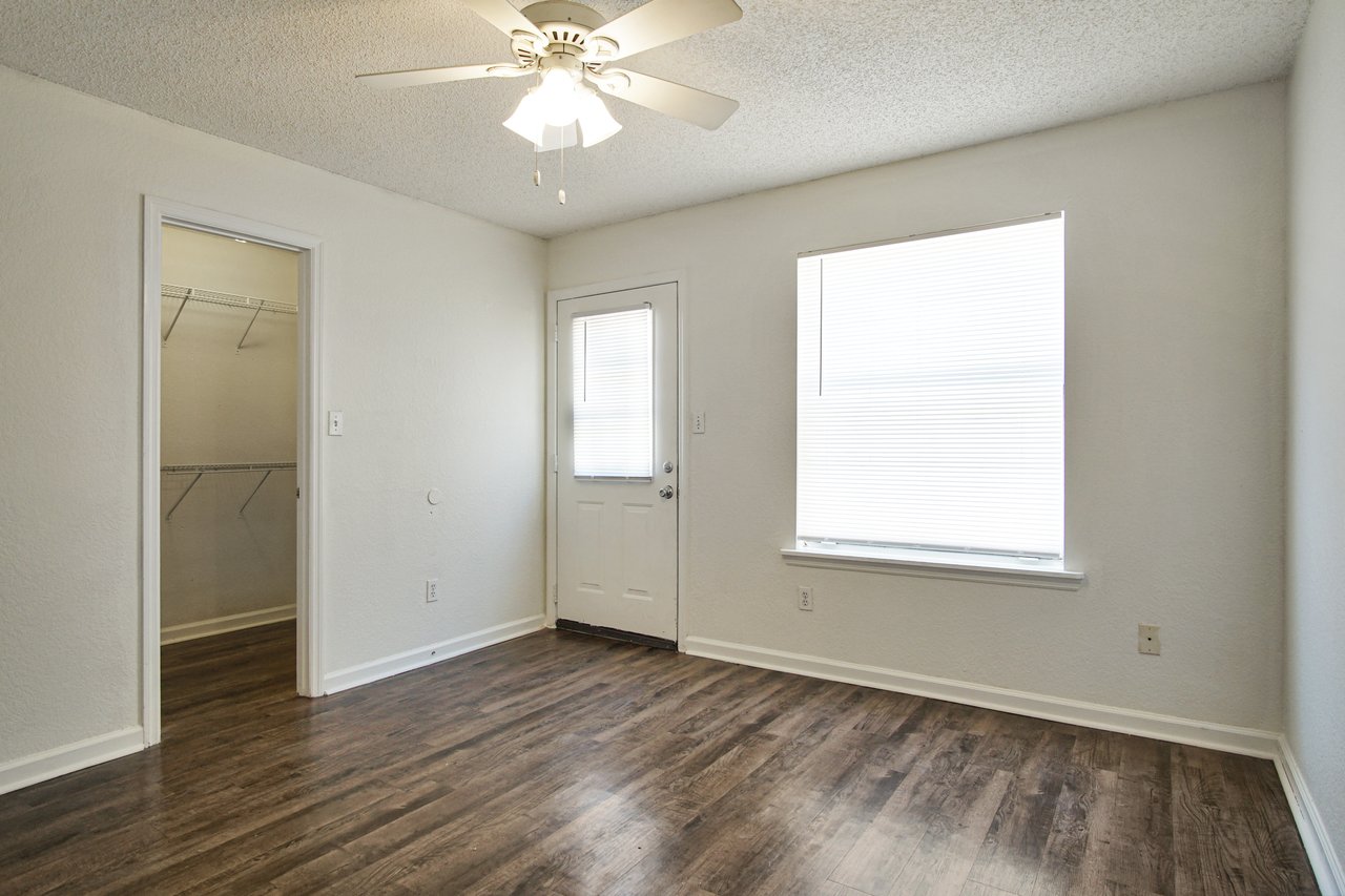 Empty room featuring hardwood floors and a ceiling fan, creating a spacious and airy atmosphere.