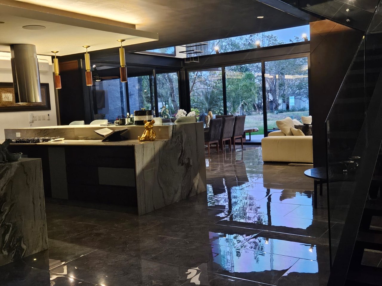 Open-plan kitchen and living area with a veined-stone island and floor-to-ceiling garden windows.
