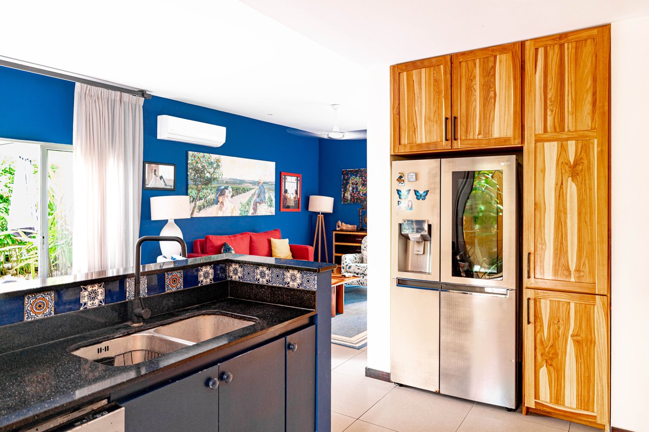 Kitchen with granite peninsula and patterned tile backsplash opening into a living room with a blue wall.
