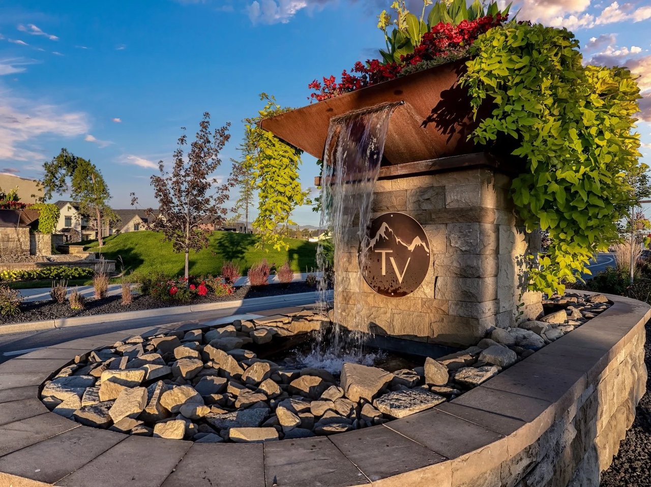 Terra View entrance fountain with a stone monument, cascading water, and landscaped homes behind it.