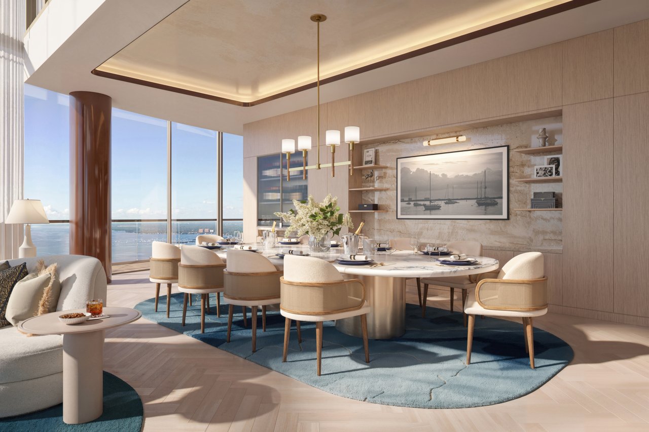 Luxury residence dining area with a marble-accented wall and floor-to-ceiling windows overlooking the water.