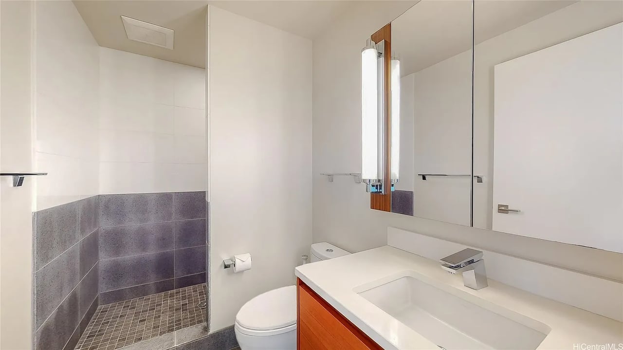 Modern bathroom with a tiled walk-in shower, white vanity, and orange-brown cabinetry.