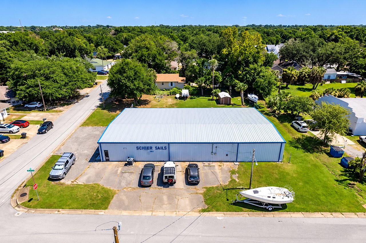 Aerial view of a commercial warehouse with a boat parked on the lawn beside it.