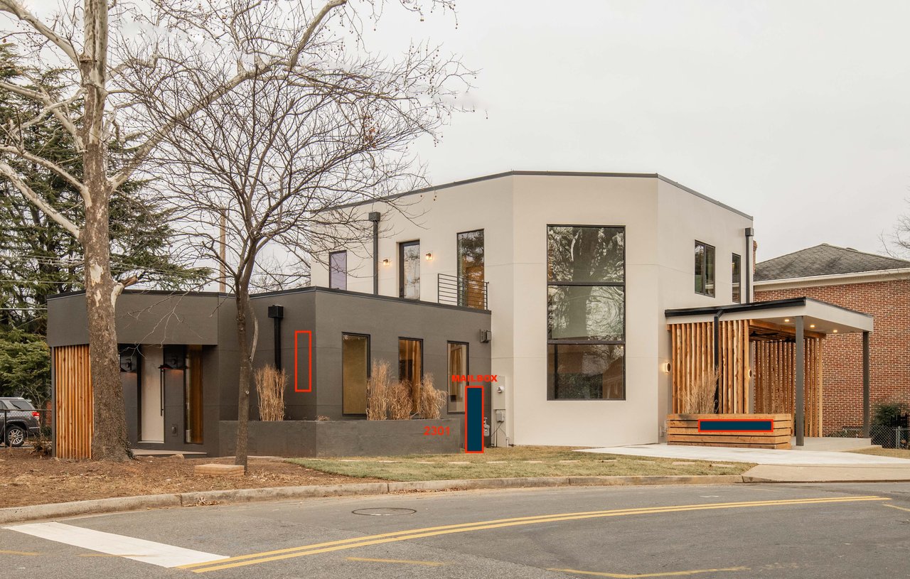 Modern two-story home with white and charcoal facades, large windows, and a wood-slat covered porch.