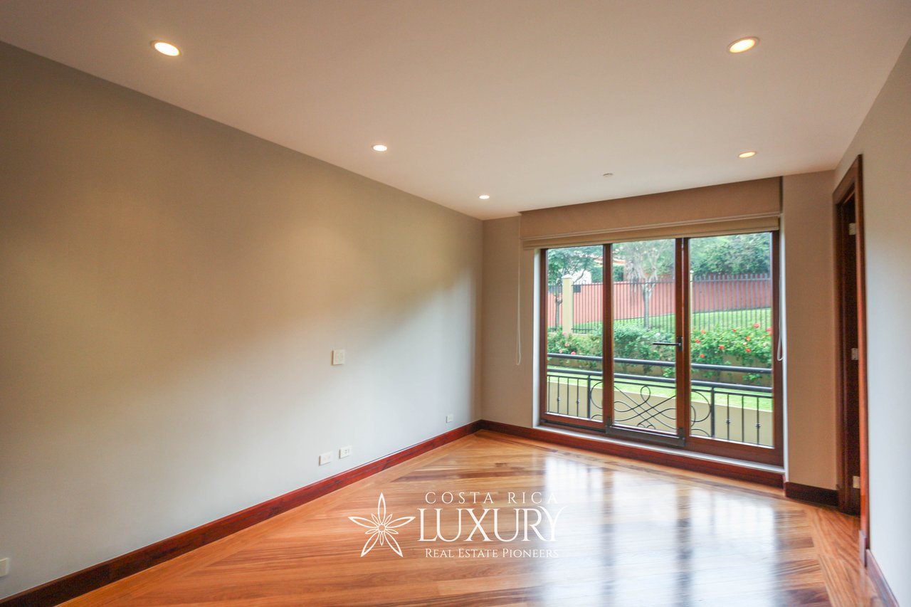 Empty apartment room with polished wood floors and sliding glass doors to a balcony.