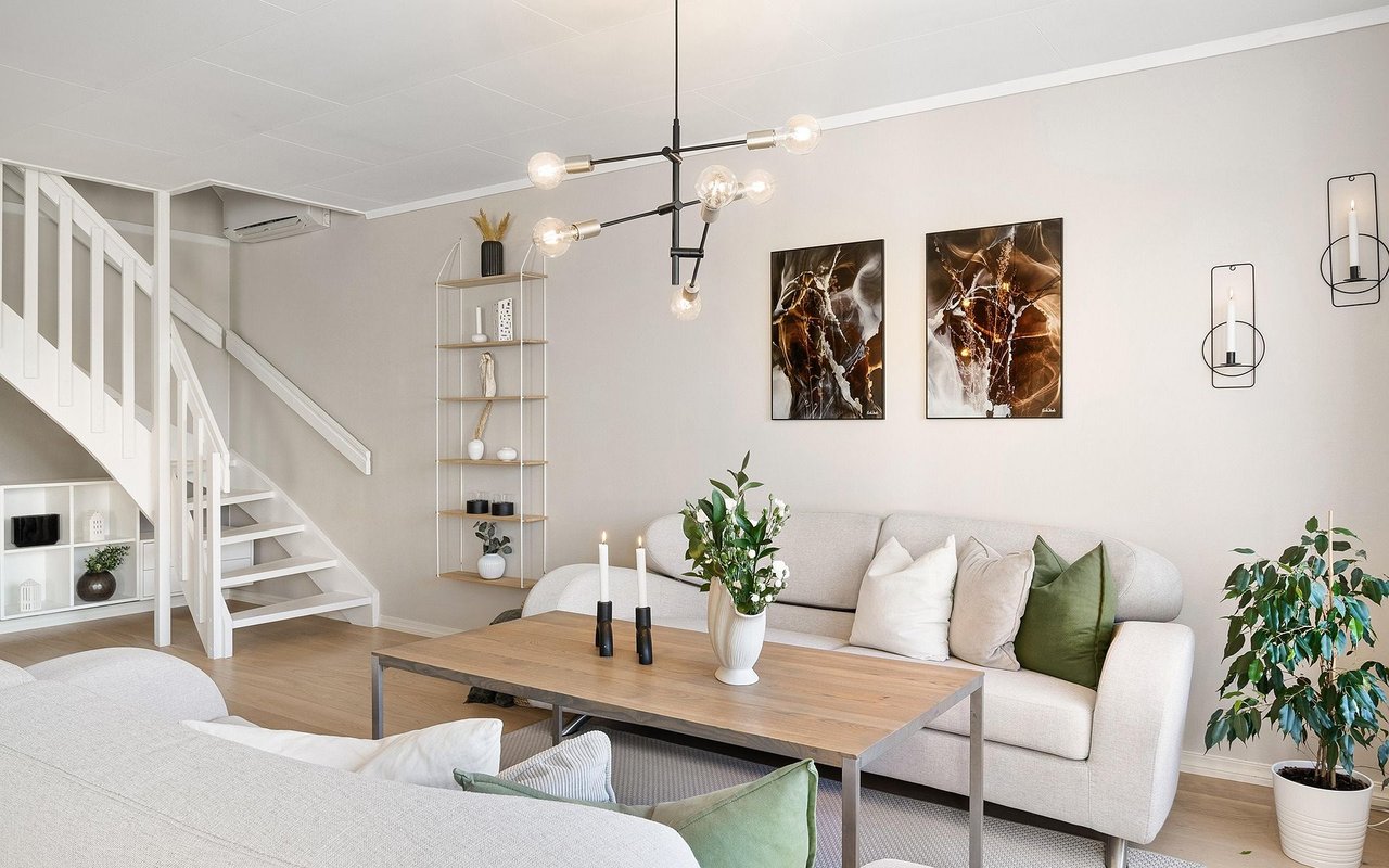 Bright living room with a white sectional, wood coffee table, and staircase with built-in shelves.