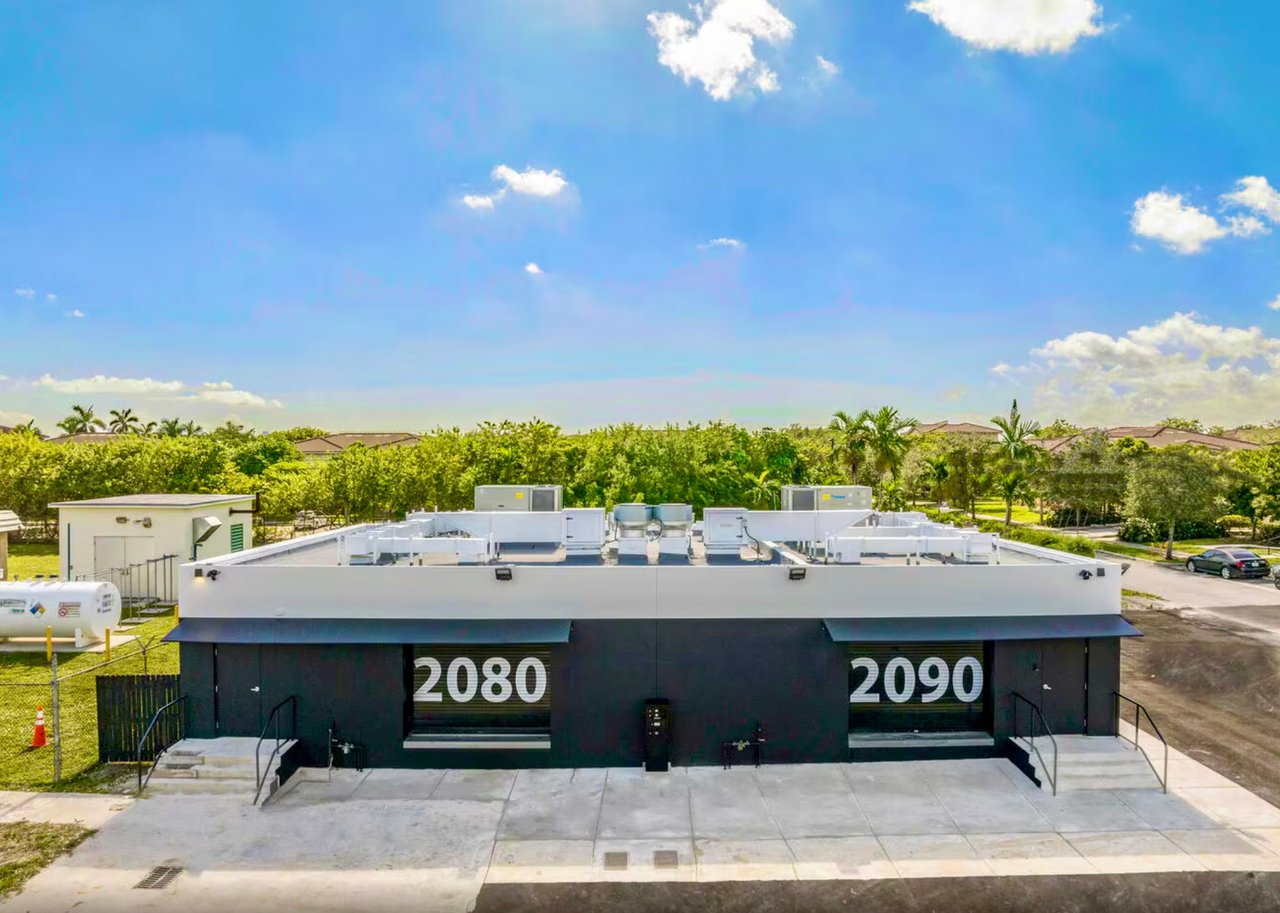 Commercial building numbered 2080 and 2090, with rooftop HVAC equipment and a paved forecourt.
