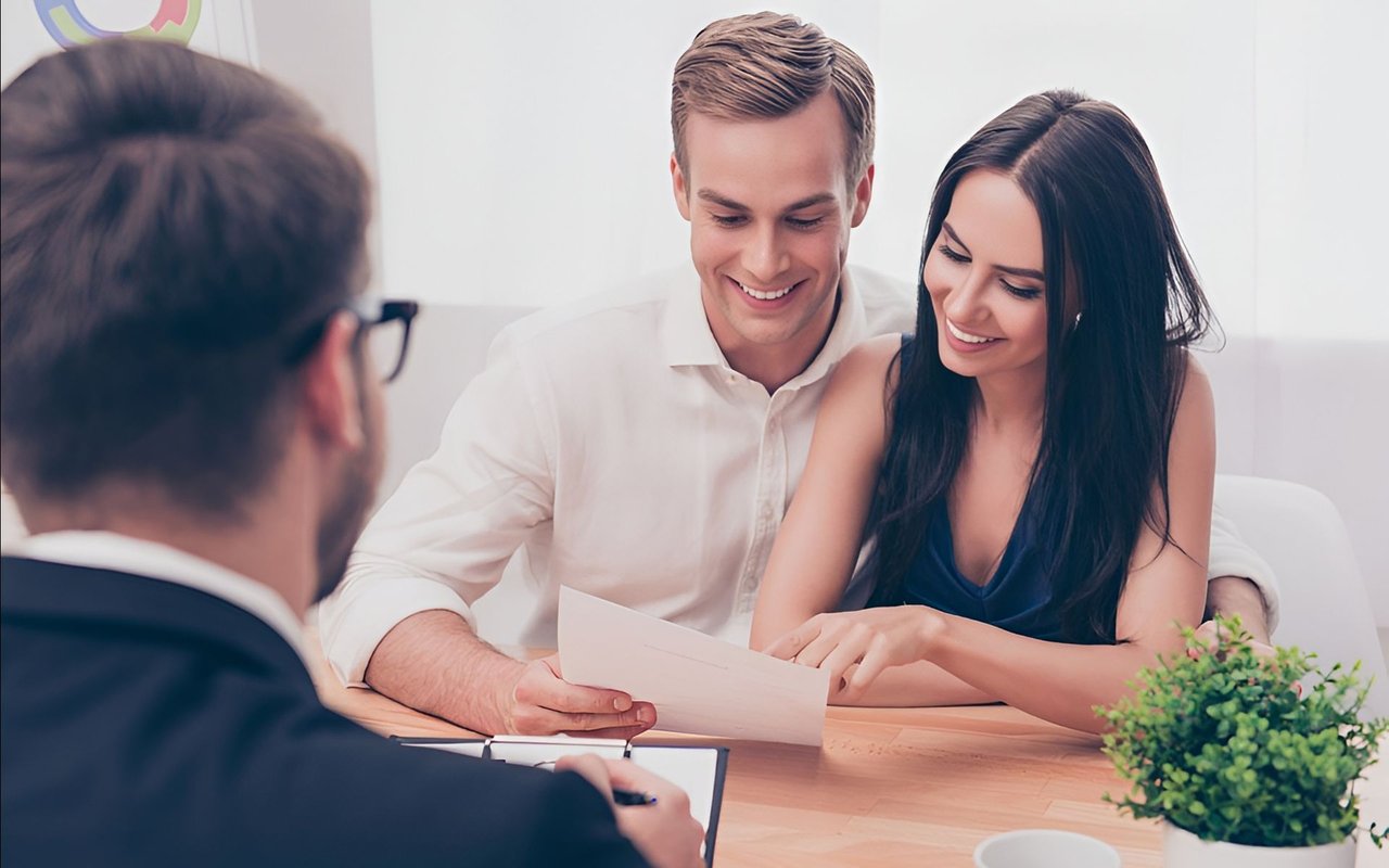A couple reviews paperwork with a loan officer during a home-buying consultation.