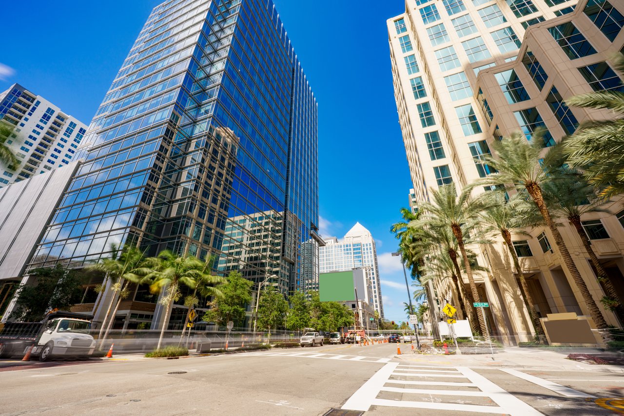 Downtown Fort Lauderdale street framed by glass towers and palm trees.