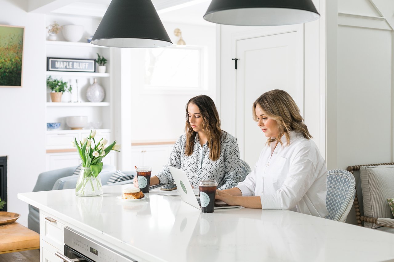 Cait Berry of Insiders Realty sitting with a buyer at a kitchen island in a bright Madison home, reviewing the home buying process together on a laptop, representing the structured, step-by-step approach Insiders Realty brings to first-time home buyers in Madison and Dane County.