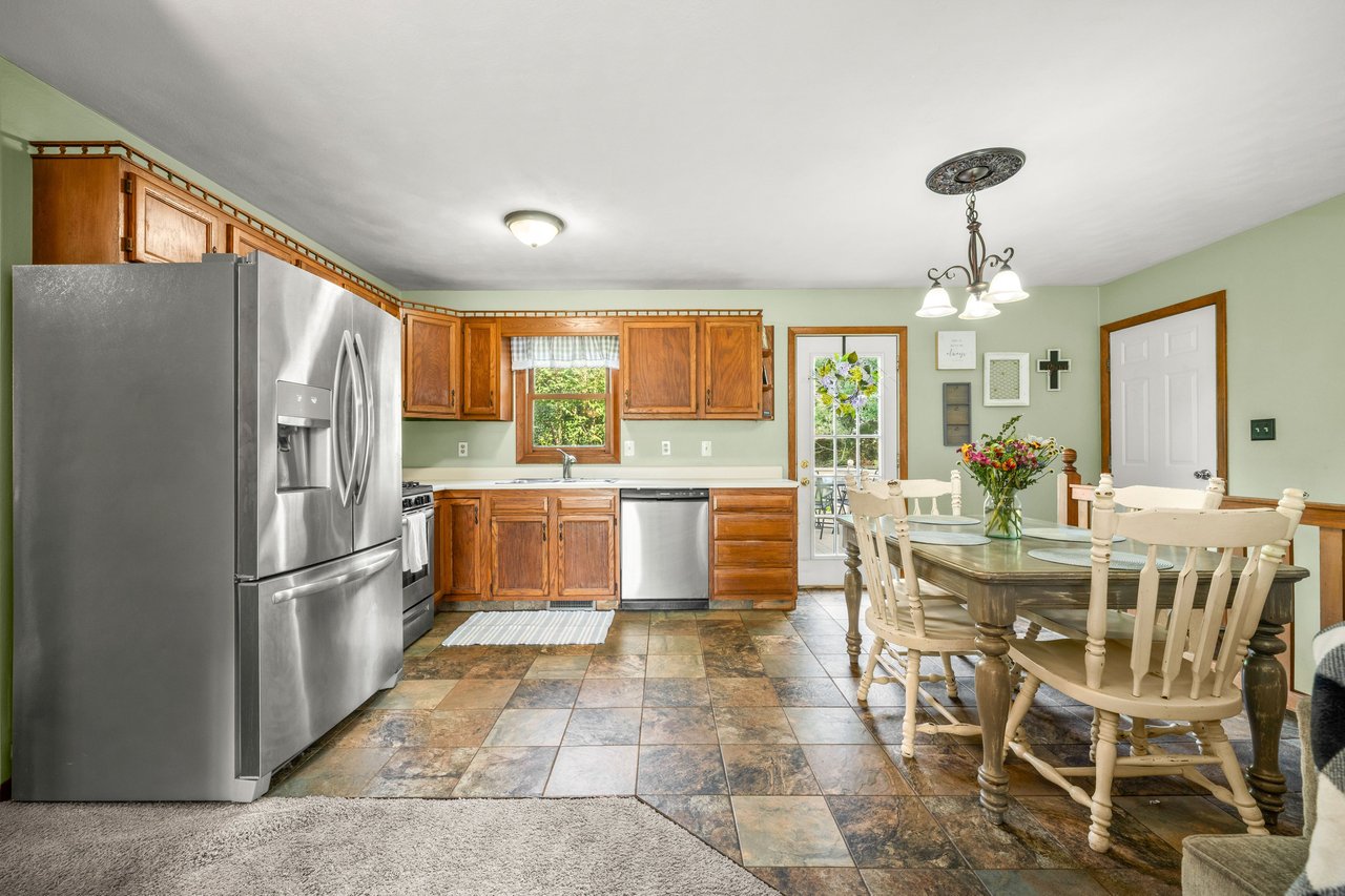 Kitchen and dining area with wood cabinets, stainless appliances, and a tiled floor.