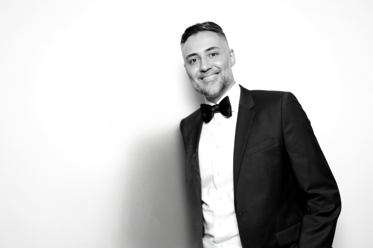Mani Ayatollahi smiling in a black tuxedo and bow tie.