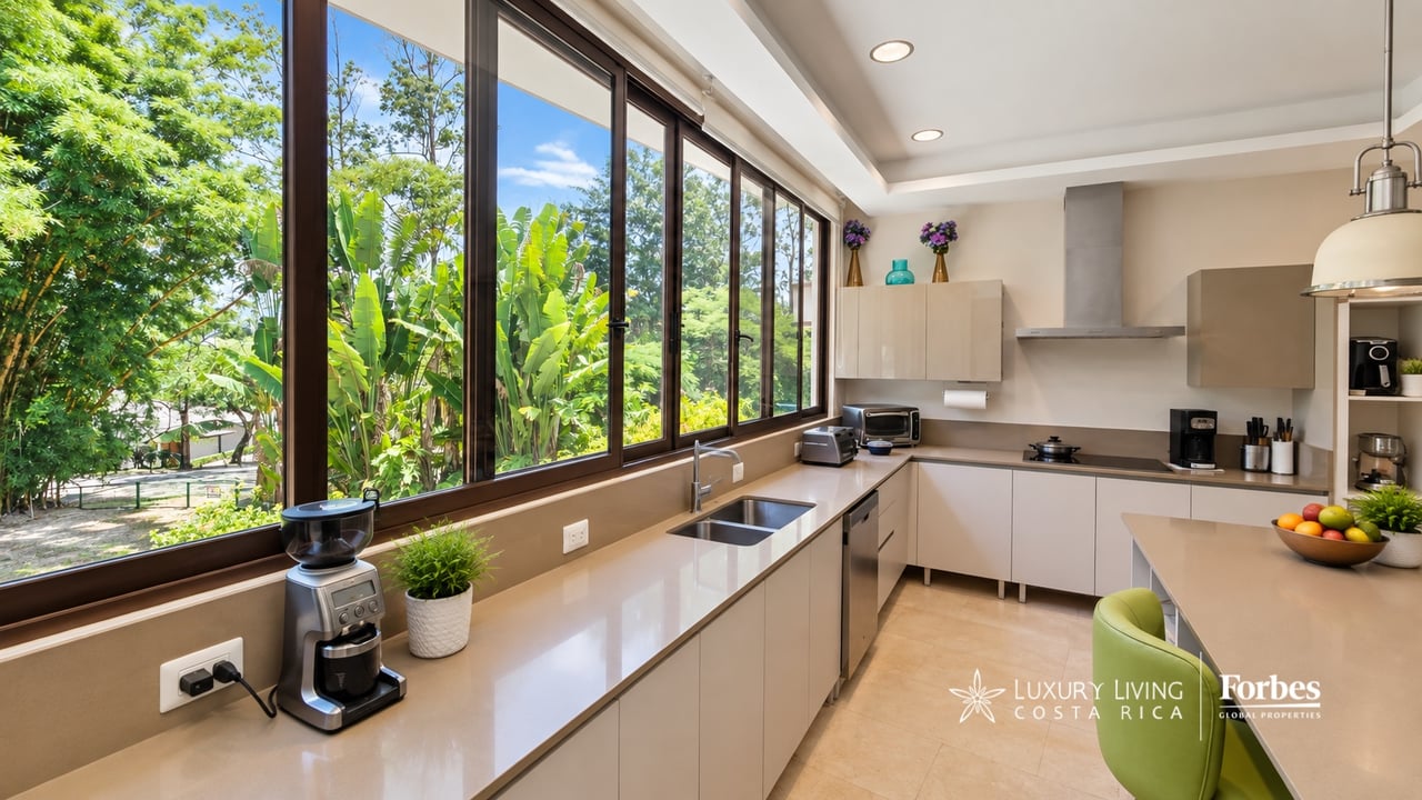 Modern kitchen with floor-to-ceiling windows overlooking a lush garden.