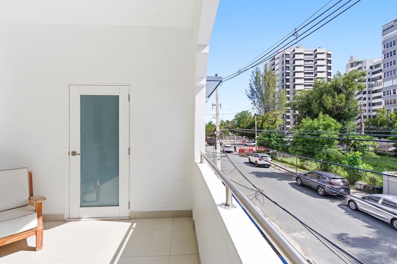 Apartment balcony overlooking a tree-lined street and neighboring high-rise buildings.