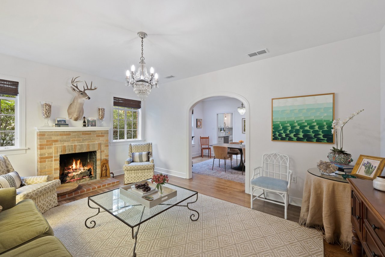 Living room with a brick fireplace, chandelier, and arched doorway to the dining room.