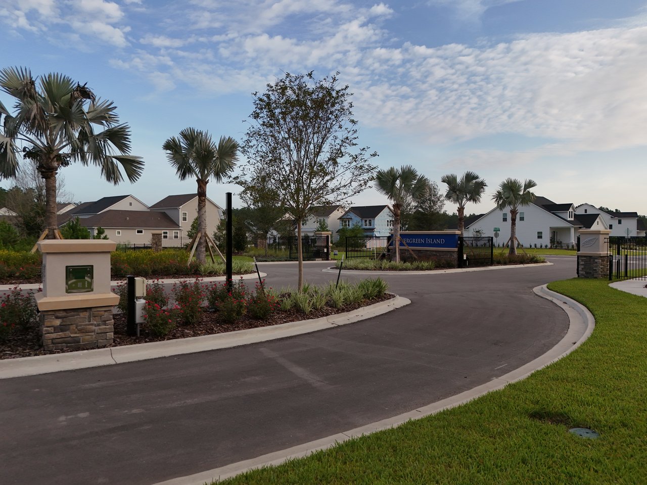 Evergreen Island neighborhood entrance with a blue sign, palm trees, and homes beyond.