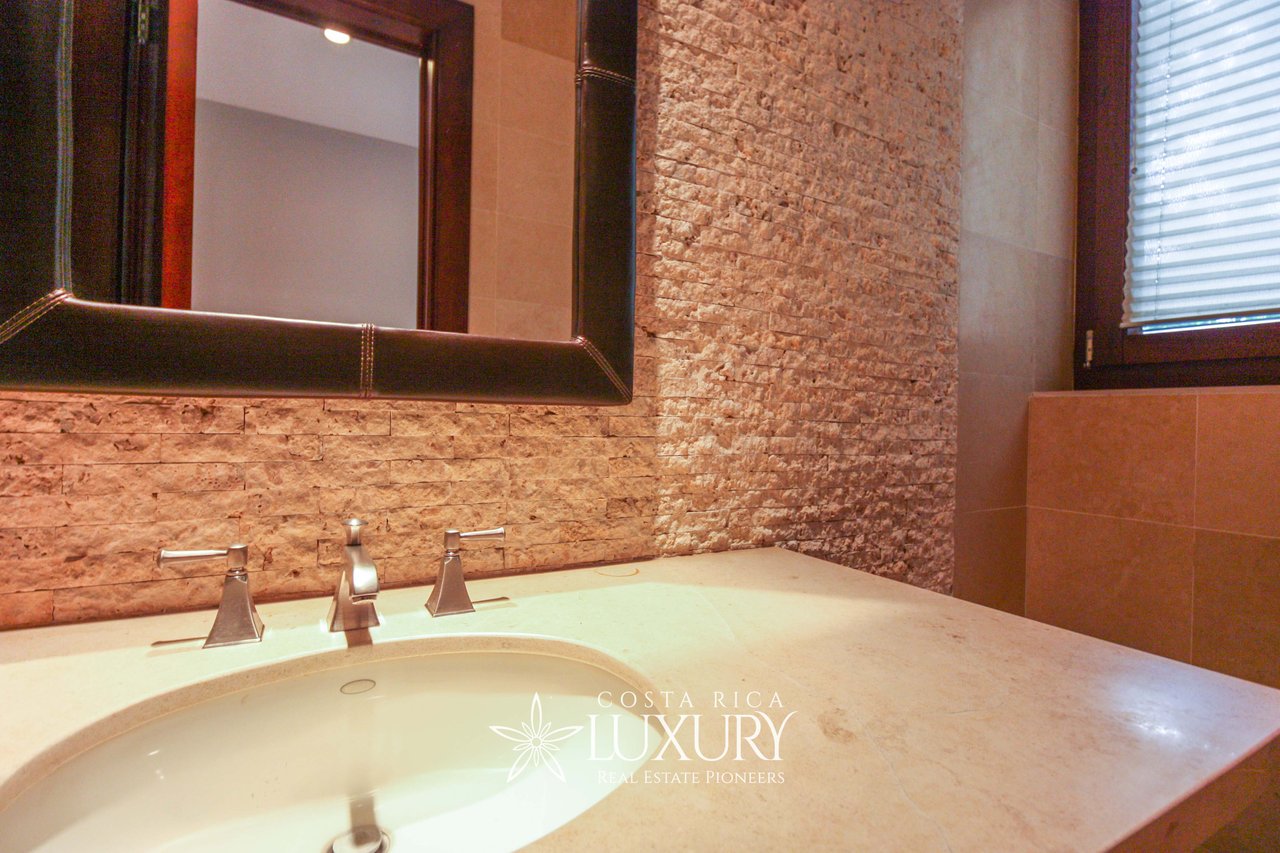 Bathroom vanity with an integrated basin, three chrome fixtures, and a textured stone wall.