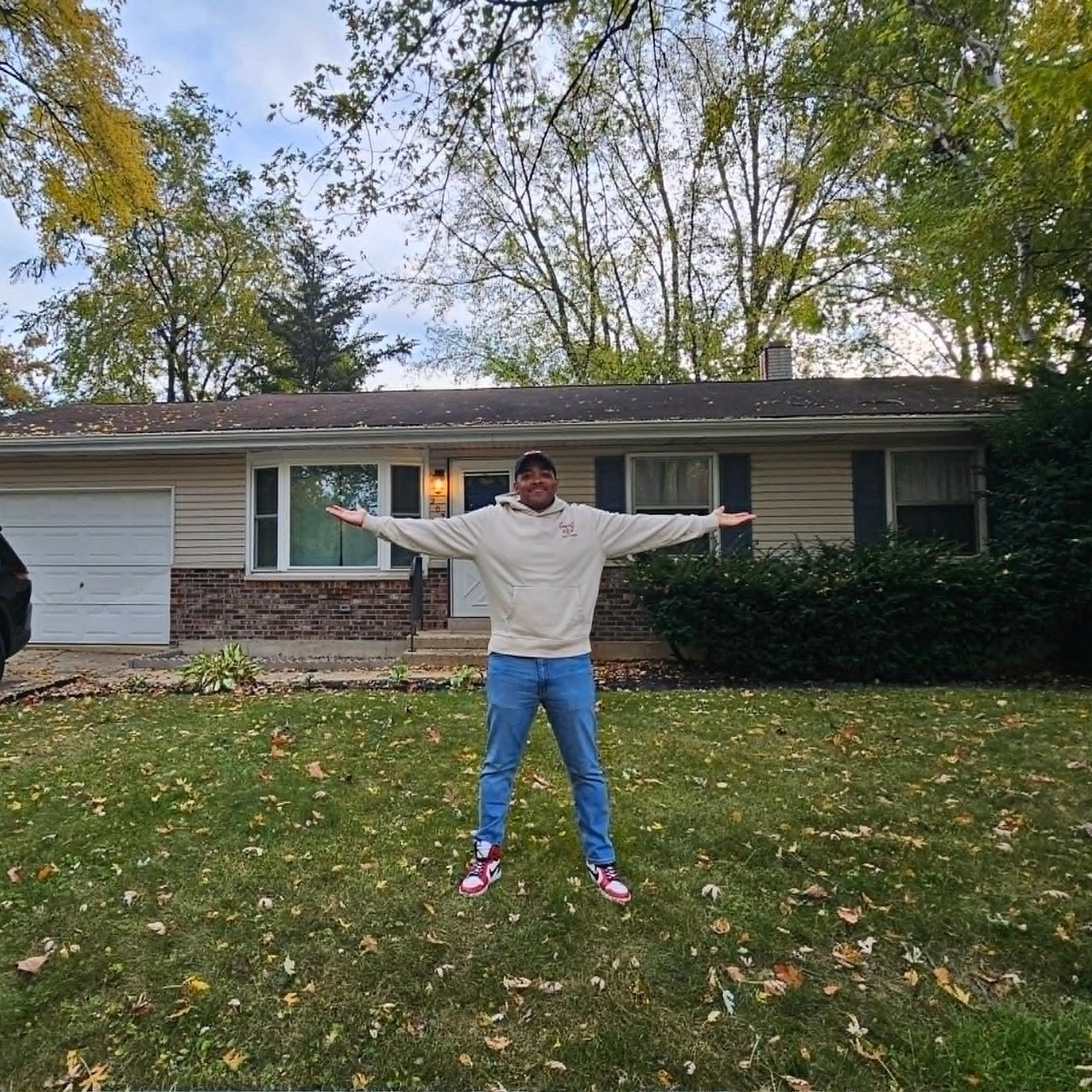 Ranch-style home with brick facade and attached garage, viewed across a leaf-strewn lawn.