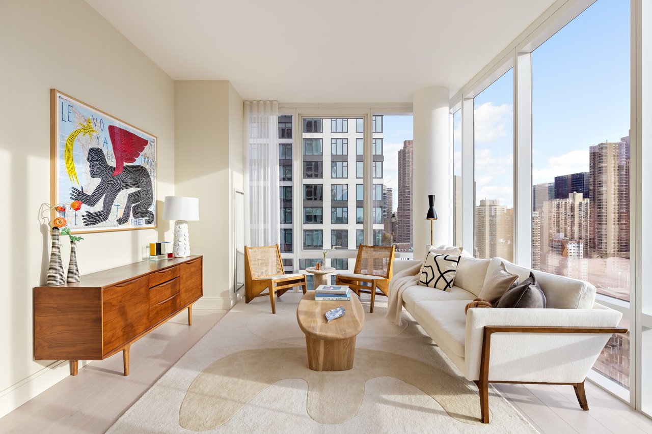 Furnished living room with floor-to-ceiling windows overlooking the city skyline.