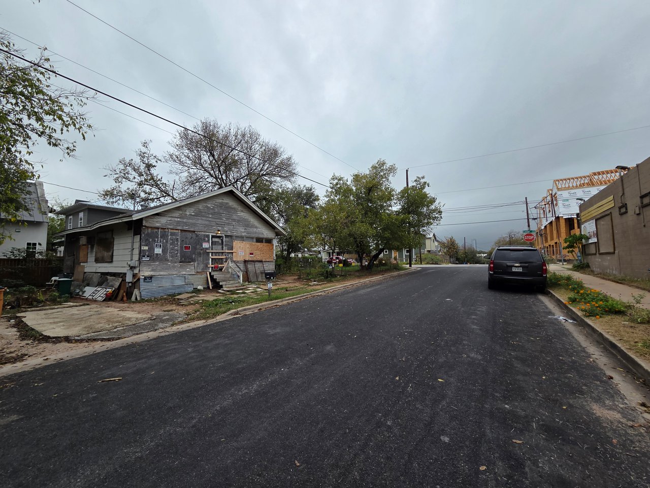 Residential street with a boarded house and a new building under construction.