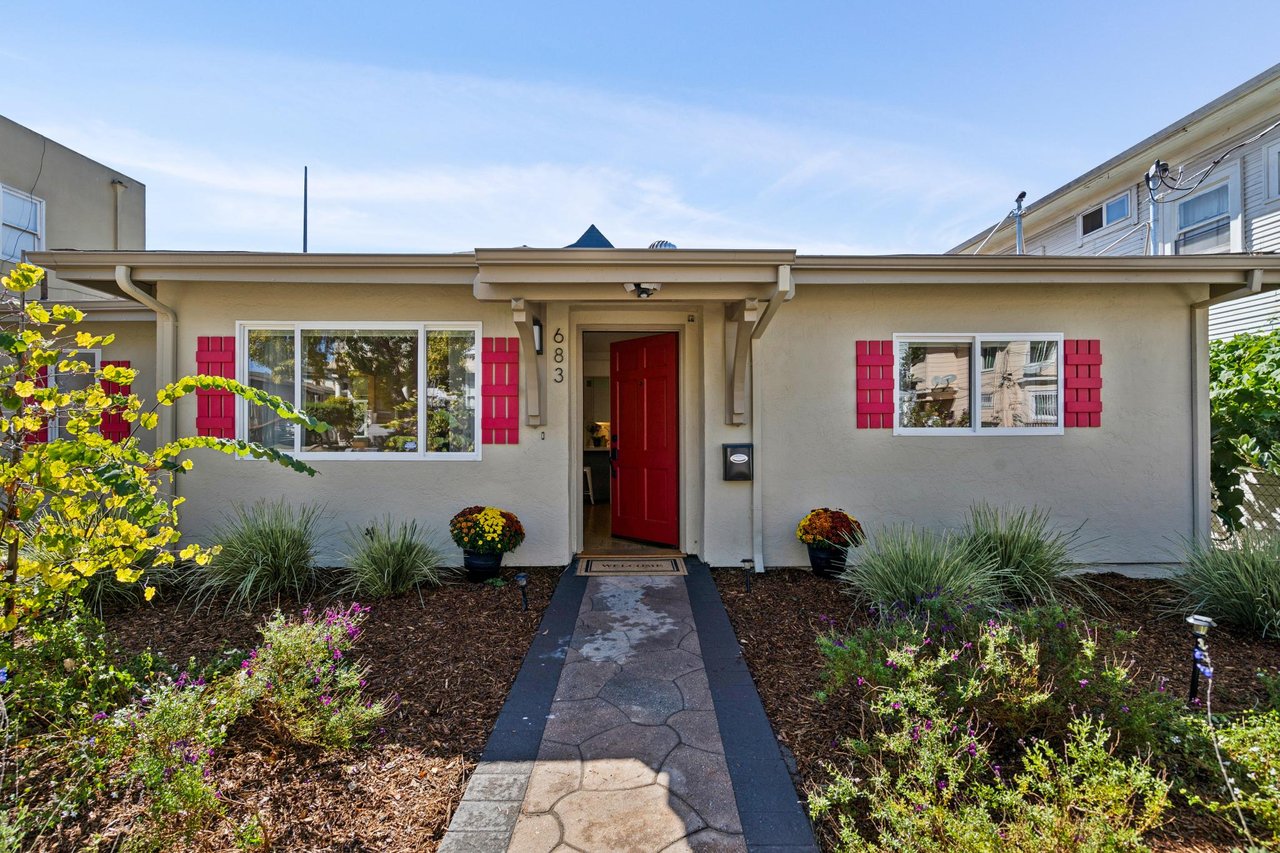 Home front with a red entry door, matching shutters, and a landscaped walkway.