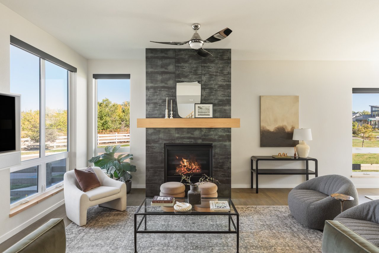 Living room centered on the fireplace, flanked by windows, with accent chairs and a glass coffee table