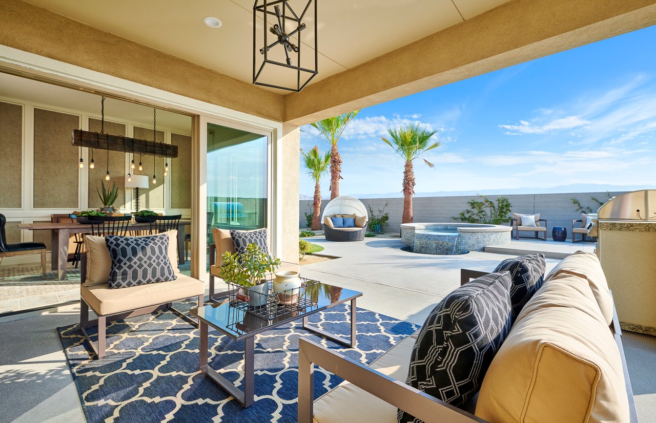 Furnished patio with cushioned seating, dining area, palm trees, and a round spa.