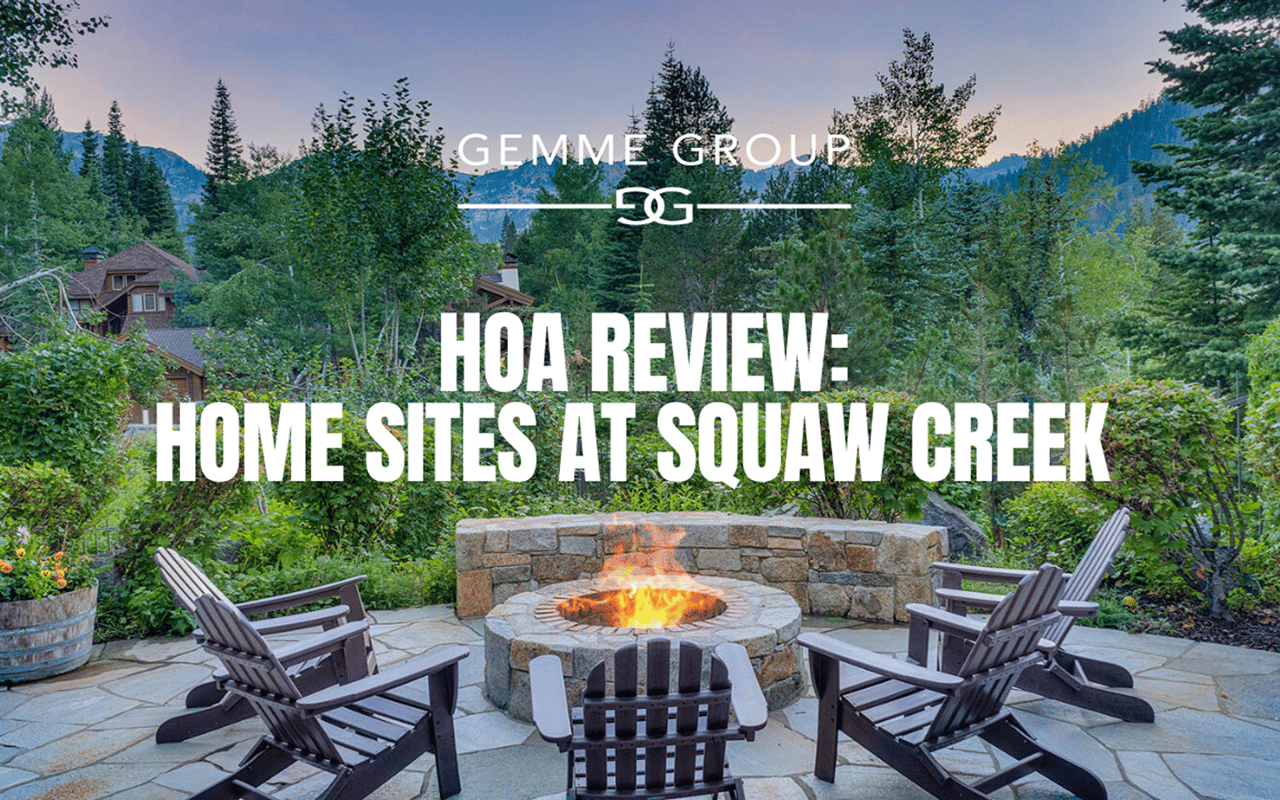 Stone patio with Adirondack chairs around a lit fire pit, backed by trees and mountain slopes.