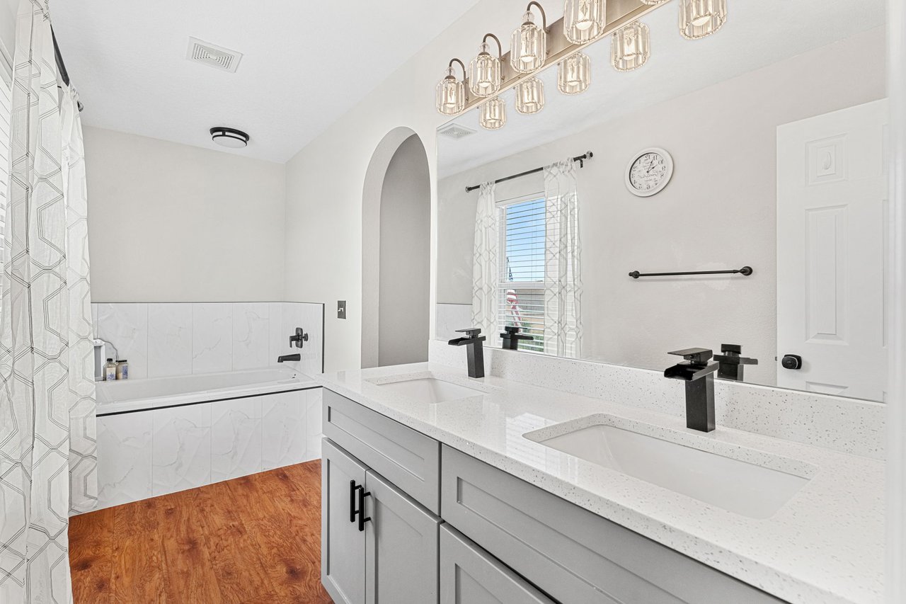 Remodeled primary bathroom with double vanity and soaking tub
