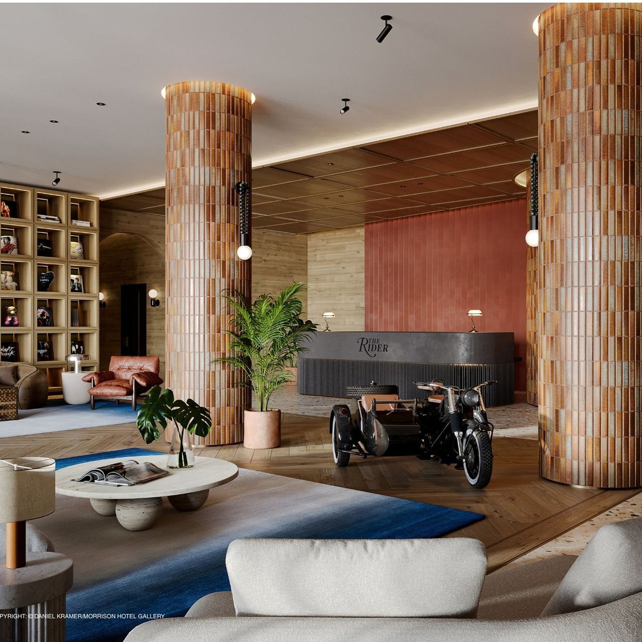 The Rider Residences lobby with tiled columns, lounge seating, and a motorcycle display.