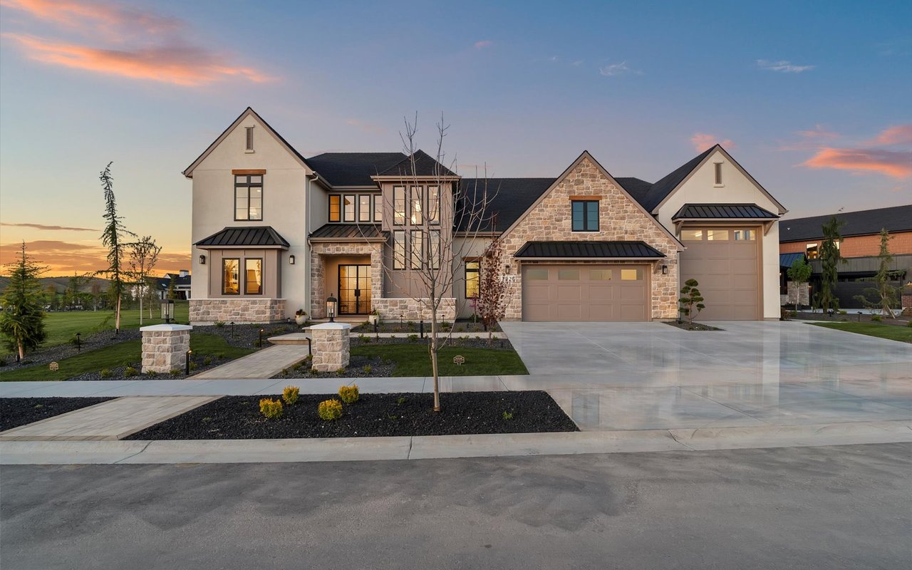 Front exterior of modern European-style home featuring neutral stonework, plaster and black windows