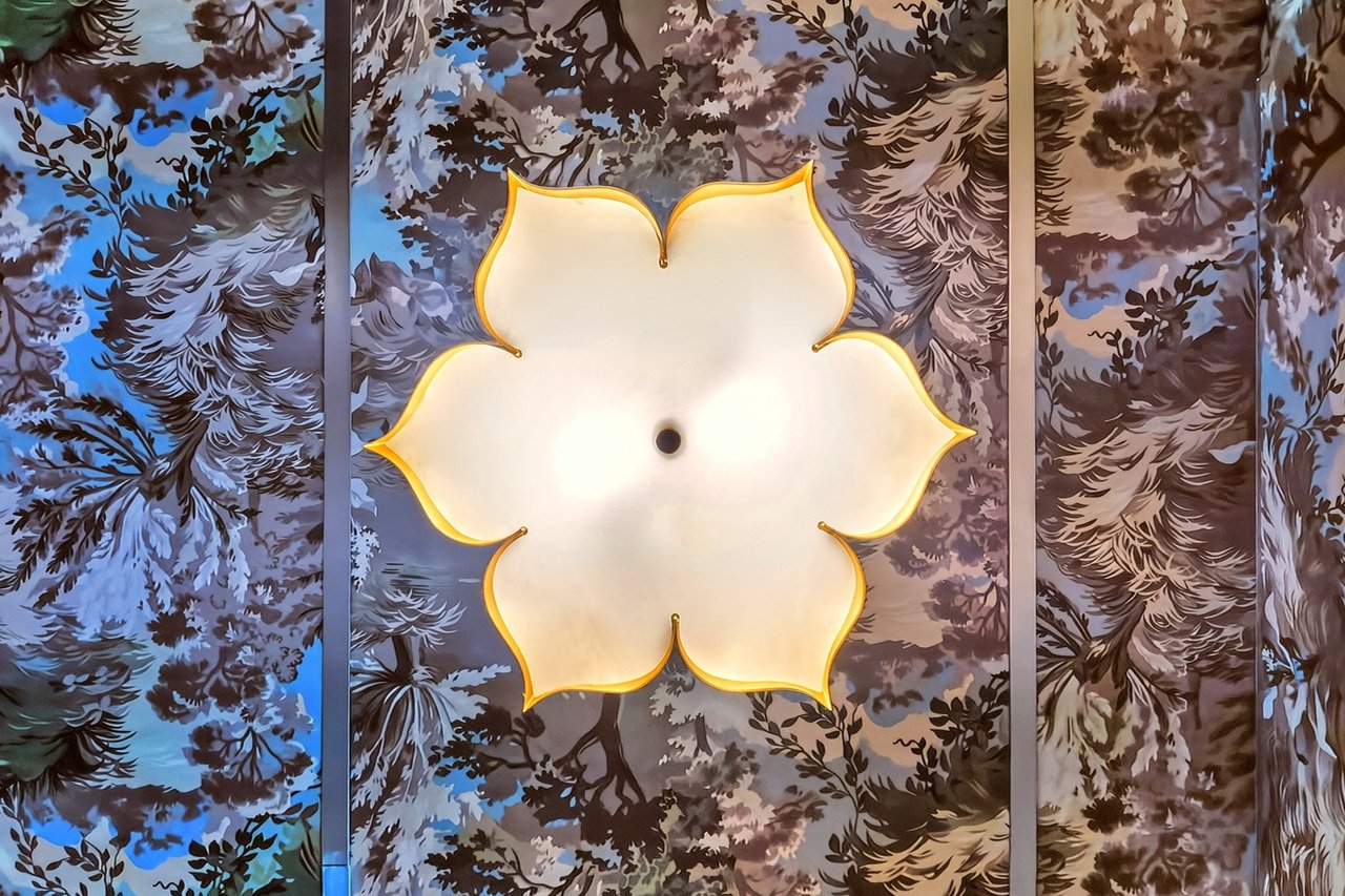 Flower-shaped ceiling light against botanical-patterned wall panels.