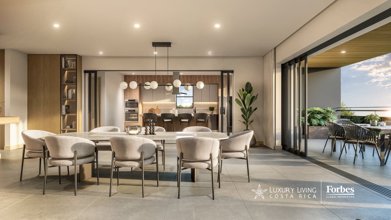 Furnished apartment dining room with a long table, wood-accented kitchen, and open terrace.